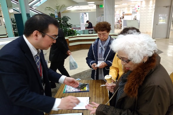 A group of people are huddled at a table, filling out forms.
