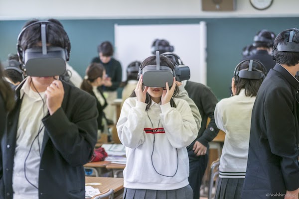 Students stand, wearing VR headsets.