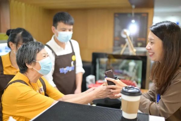 Two people, one elderly and one young, chat in a coffehouse.