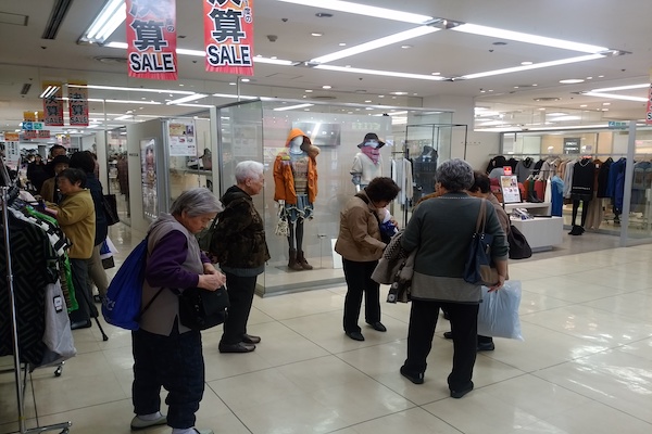 A group of elderly women shop at a clothing store.