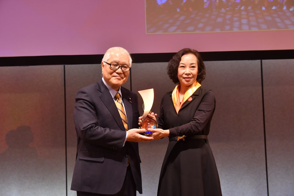 Ms. Zhang Yu, founder of Longzhen Senior Care, accepts the Grand Prize in Community-Based Innovation from Hon. Keizo Takemi
